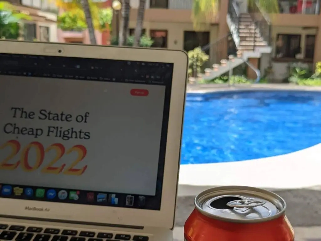 laptop open in front of a pool.